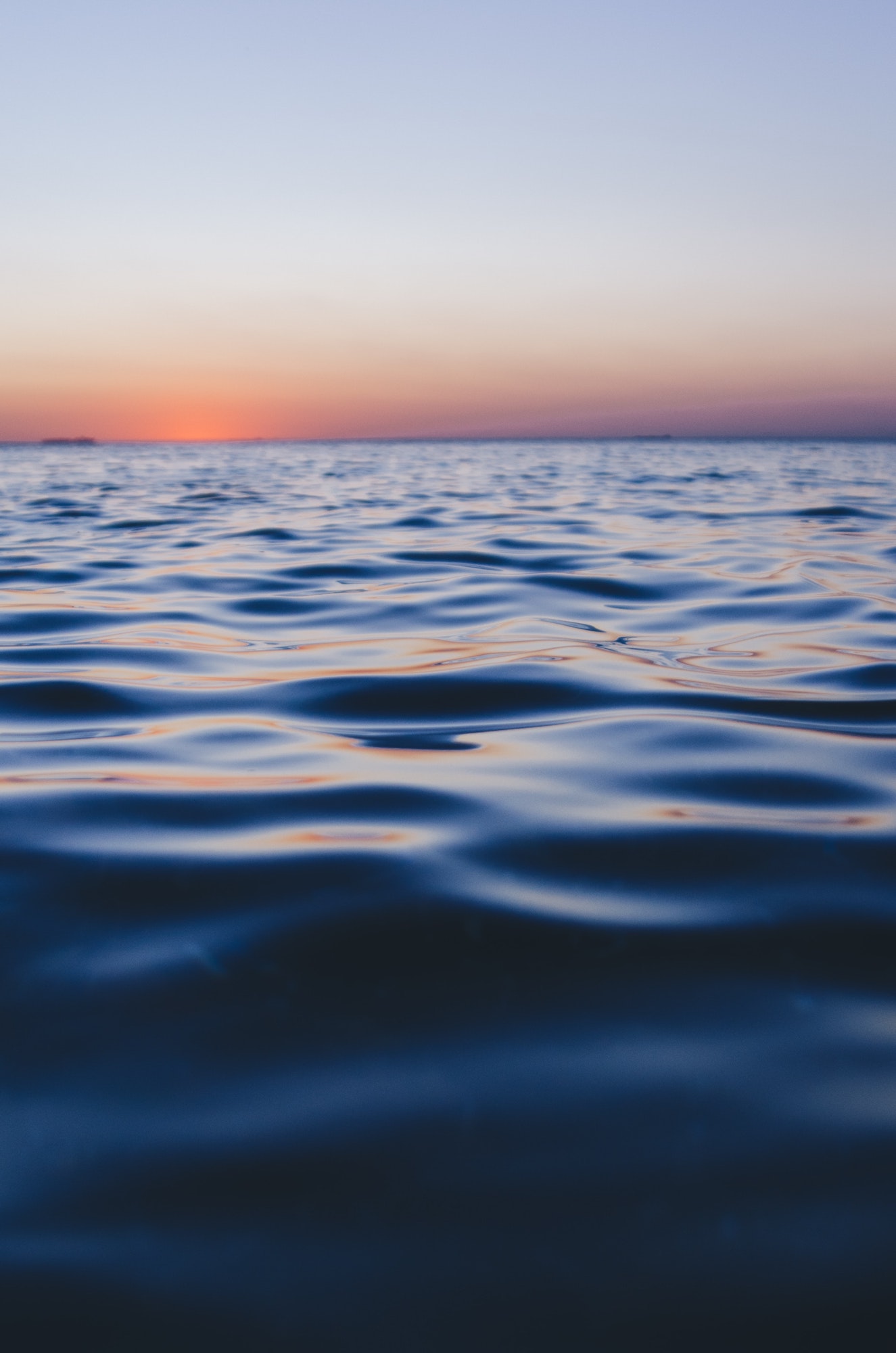 Calm open ocean water beneath a soft dusk horizon