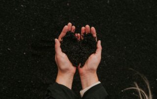 cupped hands holding dirt that forms a heart