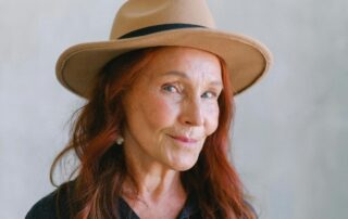 redheaded elder woman in hat with a sassy side eye to viewer.