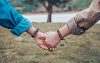 Two people holding hands while walking together outdoors, a gesture of connection