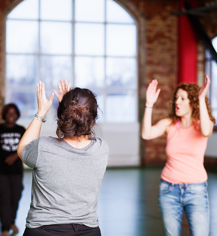 Dance movement therapy Two women moving and dancing with arms raised in a bright studio, evoking dance movement therapy