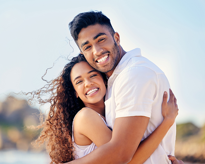 Joyful couple embracing A young couple embracing and smiling joyfully outdoors, evoking healthy relationship and connection