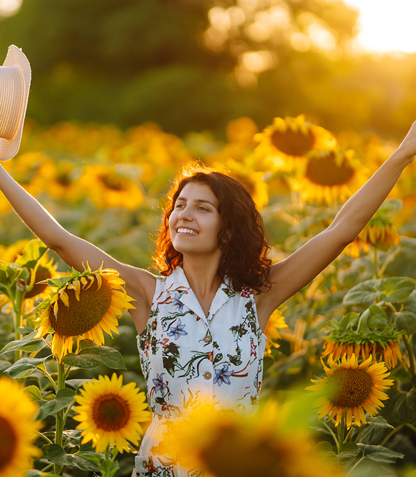 Joyful woman in a sunflower field A woman standing in a field of sunflowers with her arms raised in joy