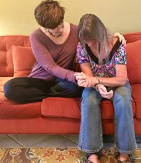 Two people seated together on a couch, one offering comforting support during a session