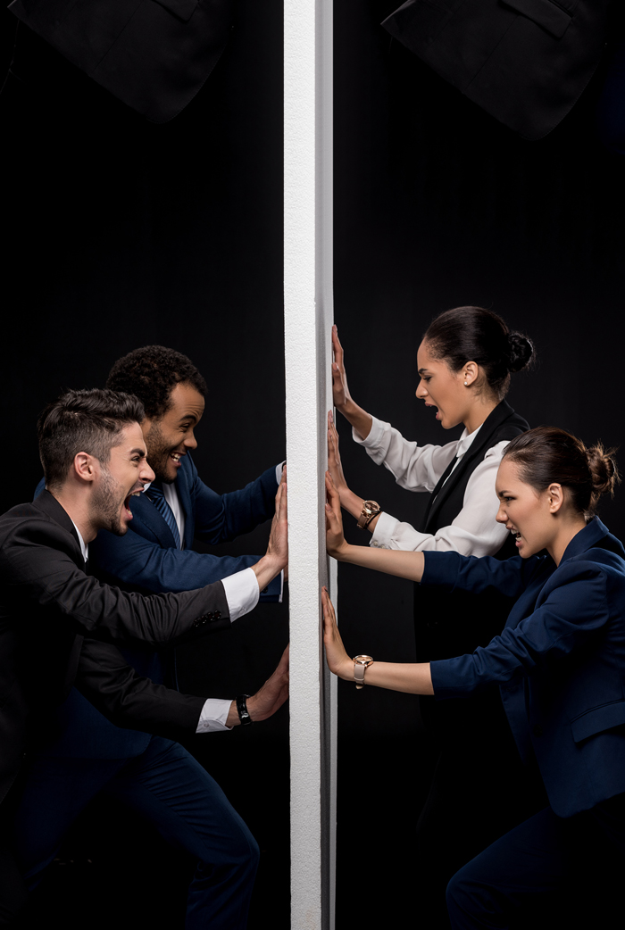 Four people pressing against opposite sides of a wall with tension, evoking conflict and boundaries