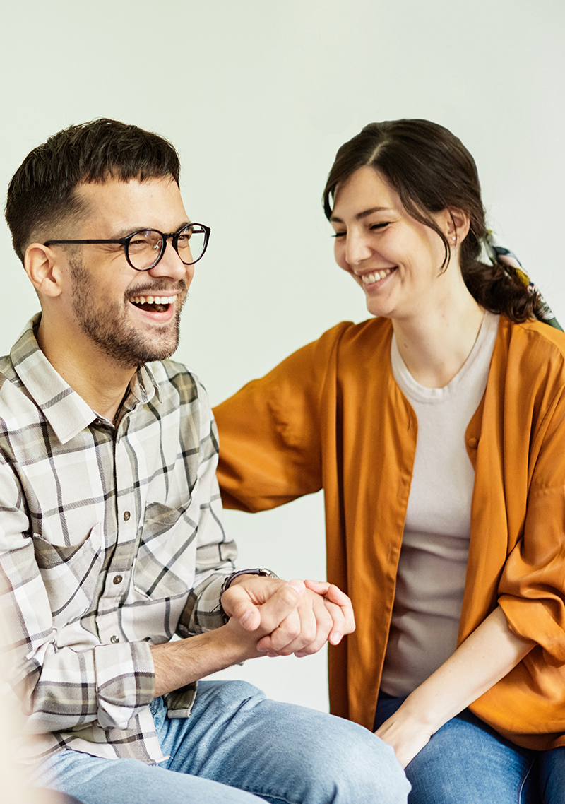 Couple laughing together A couple sitting close and laughing together, evoking joy and healthy relationship