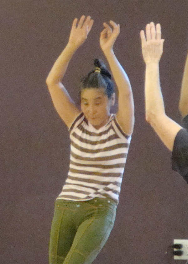 Dancing and being supported A woman moving with arms raised while others reach toward her, evoking supported movement and dance