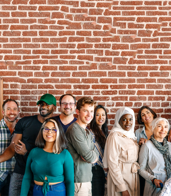 Diverse community group A diverse group of people standing together and smiling against a brick wall, evoking community