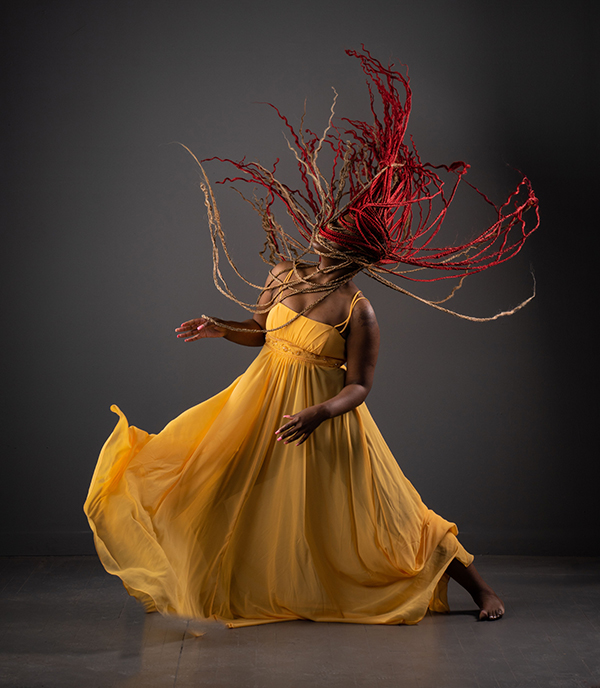 Expressive dance in a gold dress A woman in a flowing gold dress dancing dramatically with her hair flying, evoking embodied expression and movement