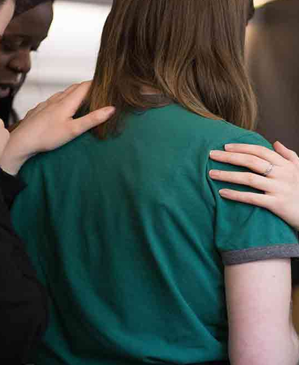 Hands of support on the back Women placing supportive hands on another woman's shoulders and back, evoking care and holding