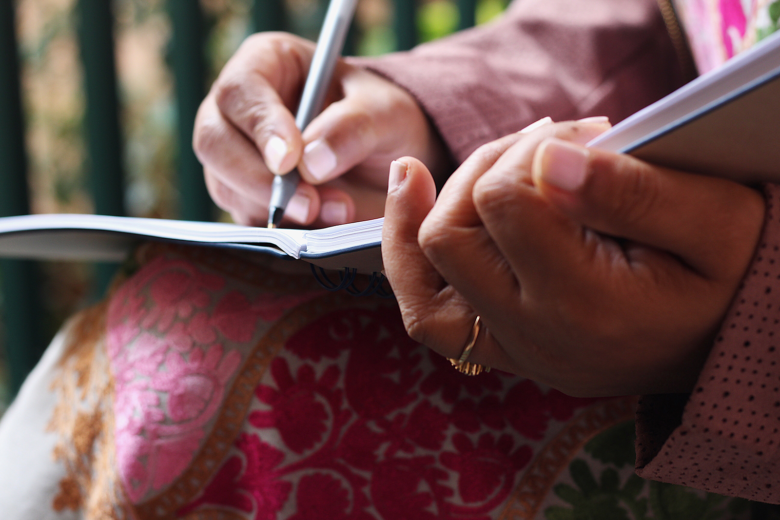 Journaling in nature A woman's hands writing in a journal on her lap outdoors, evoking reflection and storytelling
