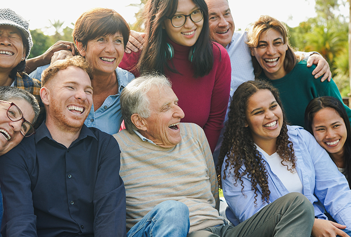 A joyful multigenerational, multiracial family gathered together and smiling, evoking family and community