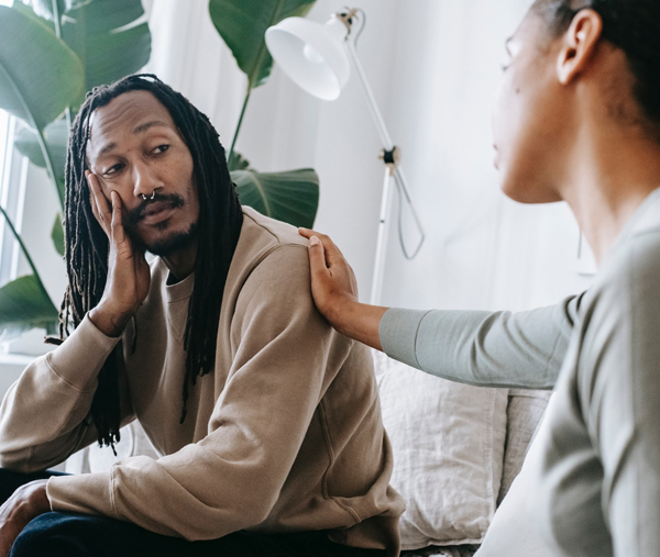 Offering comfort and support One person resting a supportive hand on the shoulder of another who looks distressed, evoking therapy and emotional support