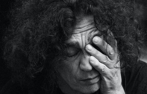 Overwhelmed, hand over face Black and white portrait of a curly-haired person with a hand over their face, looking overwhelmed