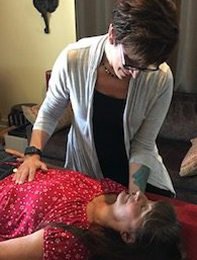Sabrina Santa Clara working gently over a person lying on a treatment table, evoking somatic bodywork and psychotherapeutic touch