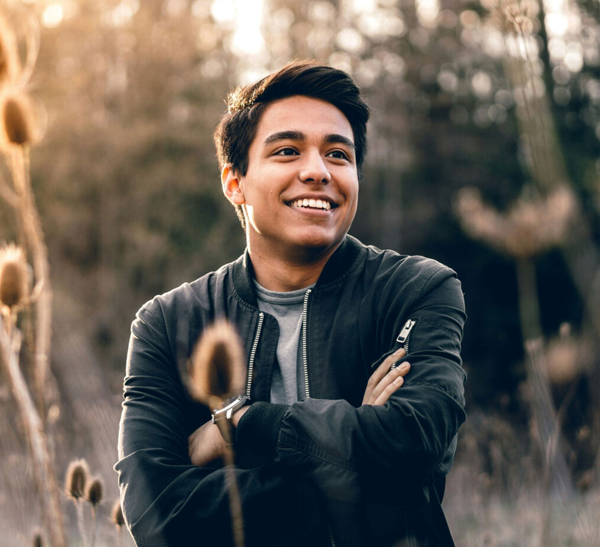 Smiling man in autumn forest A young man smiling with arms crossed in a golden autumn forest, evoking hope and wellbeing