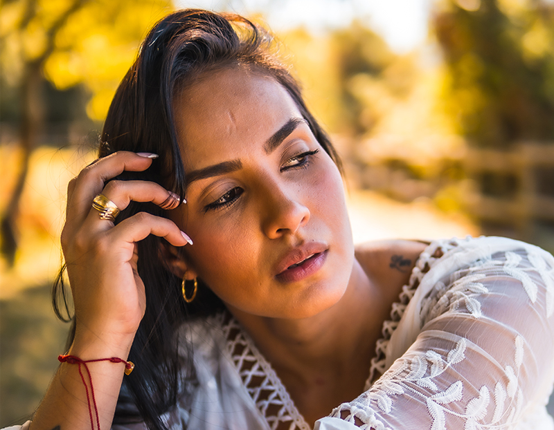 Thoughtful woman outdoors A woman resting her hand against her face in thought amid soft autumn light