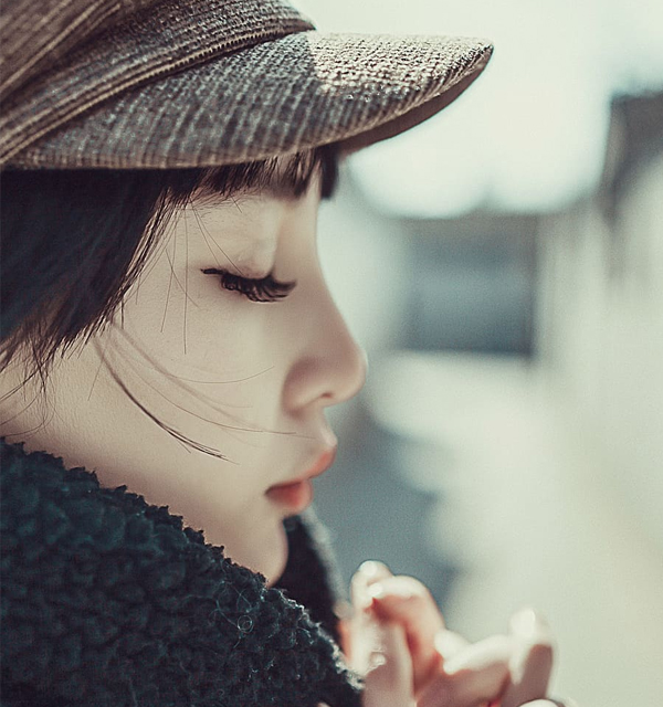 Woman in quiet contemplation A woman in a cap with eyes closed and hands near her face, in quiet contemplation