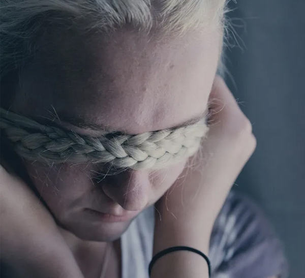 Woman with braid across her face A young woman with a braid falling across her face, head lowered, evoking trauma and grief