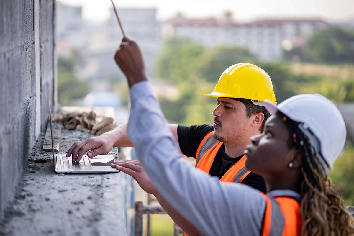 Construction workers in hard hats reviewing plans together at a work site