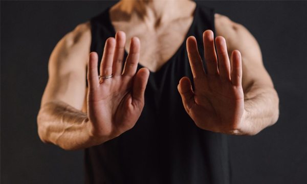 A man's torso with both hands outstretched, palms out, communicating a no-touch boundary