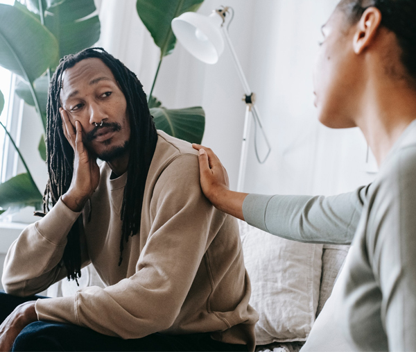 A man in a therapy session receiving a supportive hand on his shoulder from his therapist, evoking comfort and support