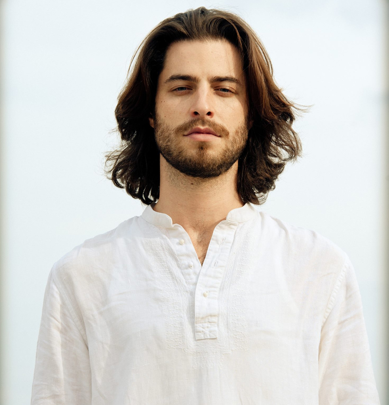 Portrait of Matt Colaciello with long hair in white linen, inviting spiritual counseling