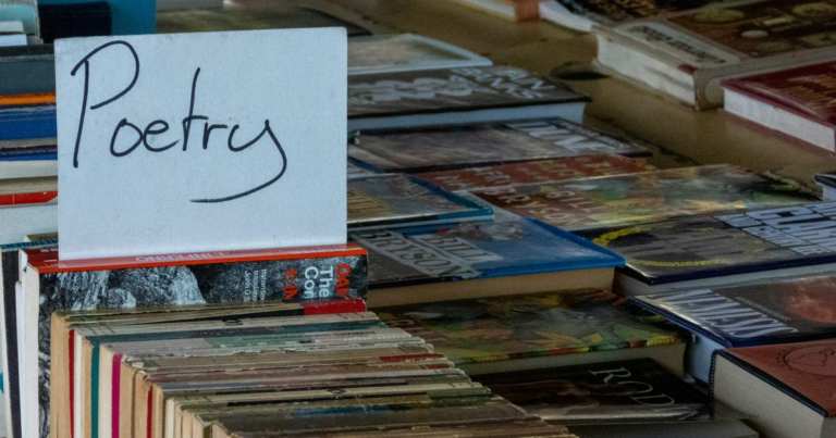 A handwritten "Poetry" sign on a table of secondhand books.
