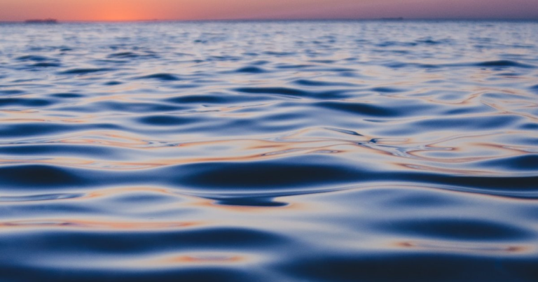Calm open ocean water beneath a soft dusk horizon.